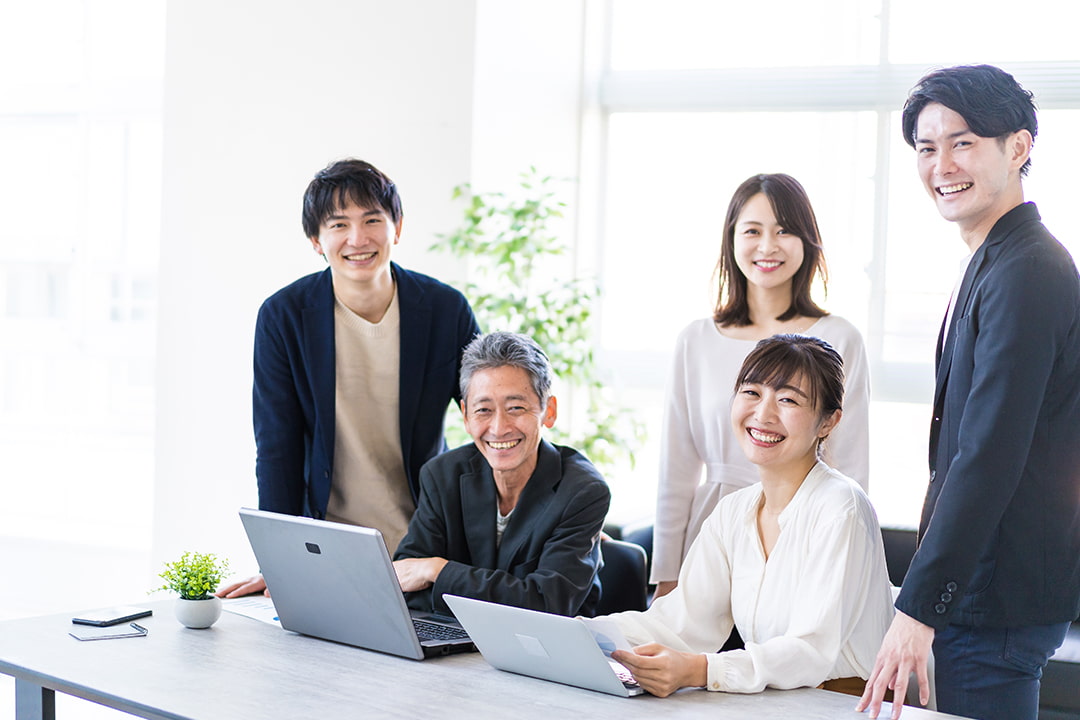 微笑んでいる年齢の違う男女の5人の社員